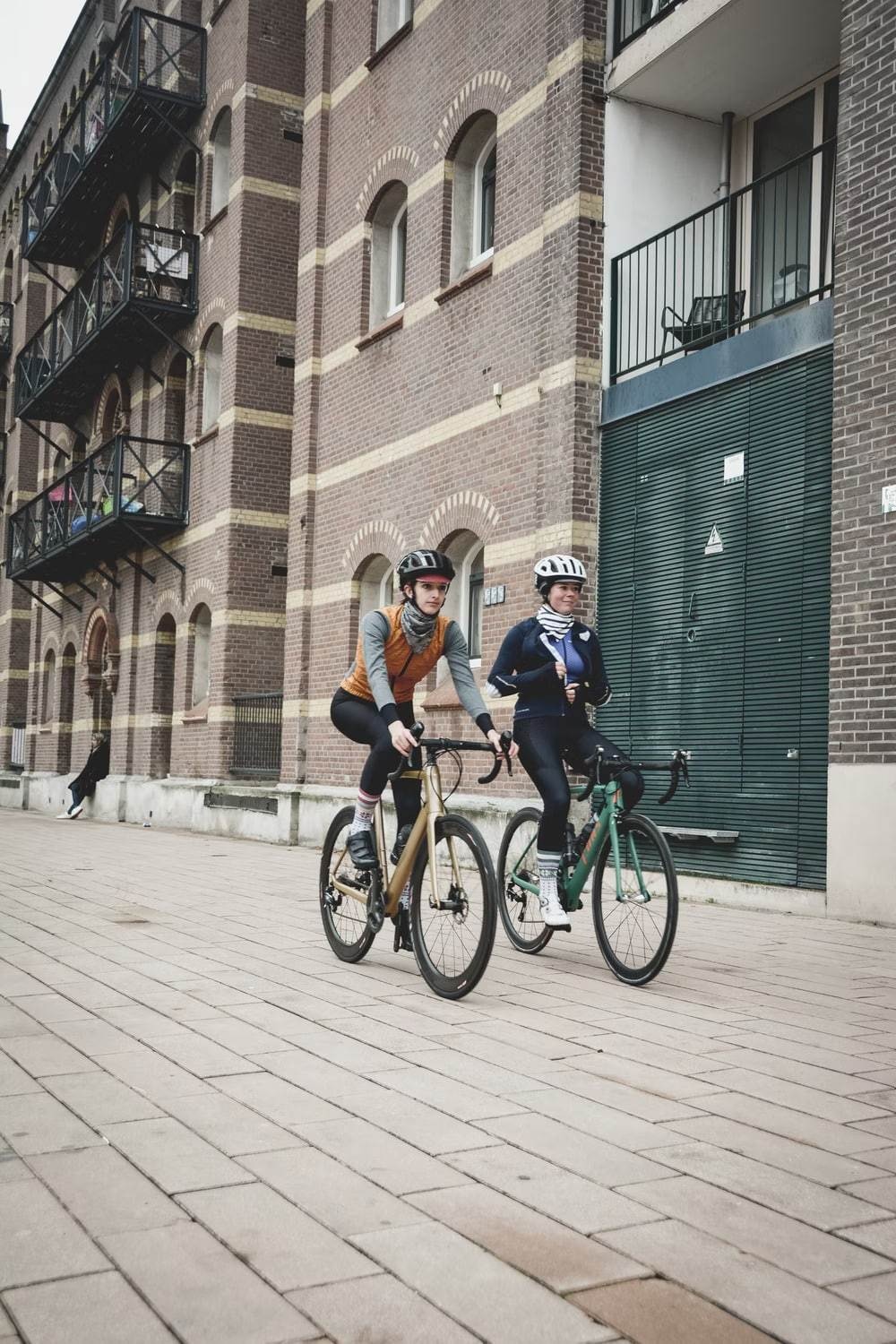 2 people riding a bicycle on a city street