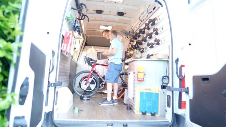 side view of cyclist and bike fitter checking saddle pressure map test results