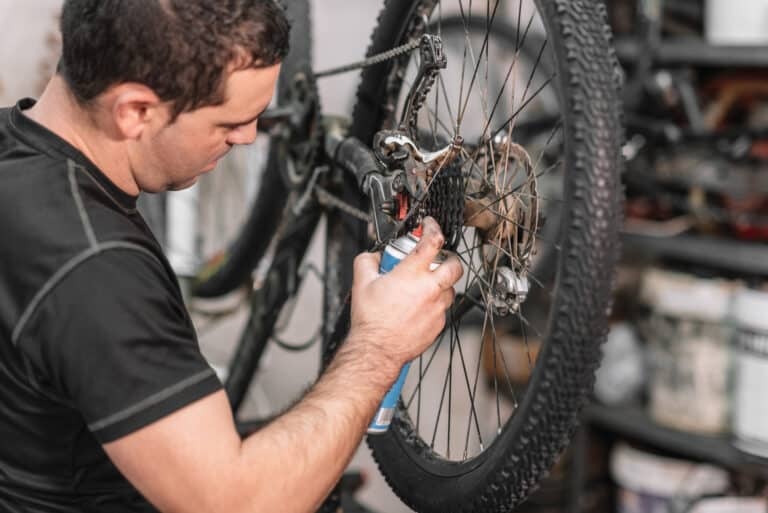Mechanic man Hands, Spraying Oil To A Bike Chain. Bicycle maintenance.