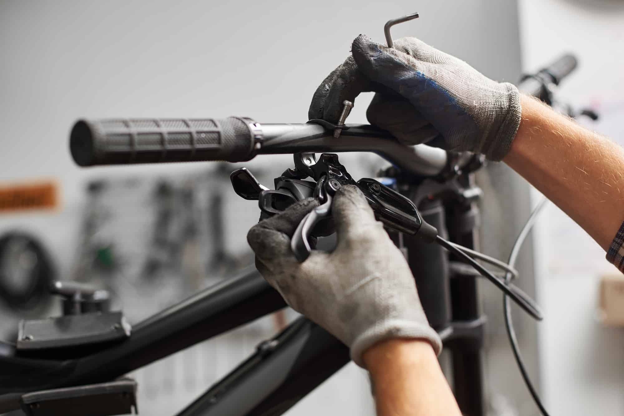 Male mechanic working in bicycle repair shop using tools