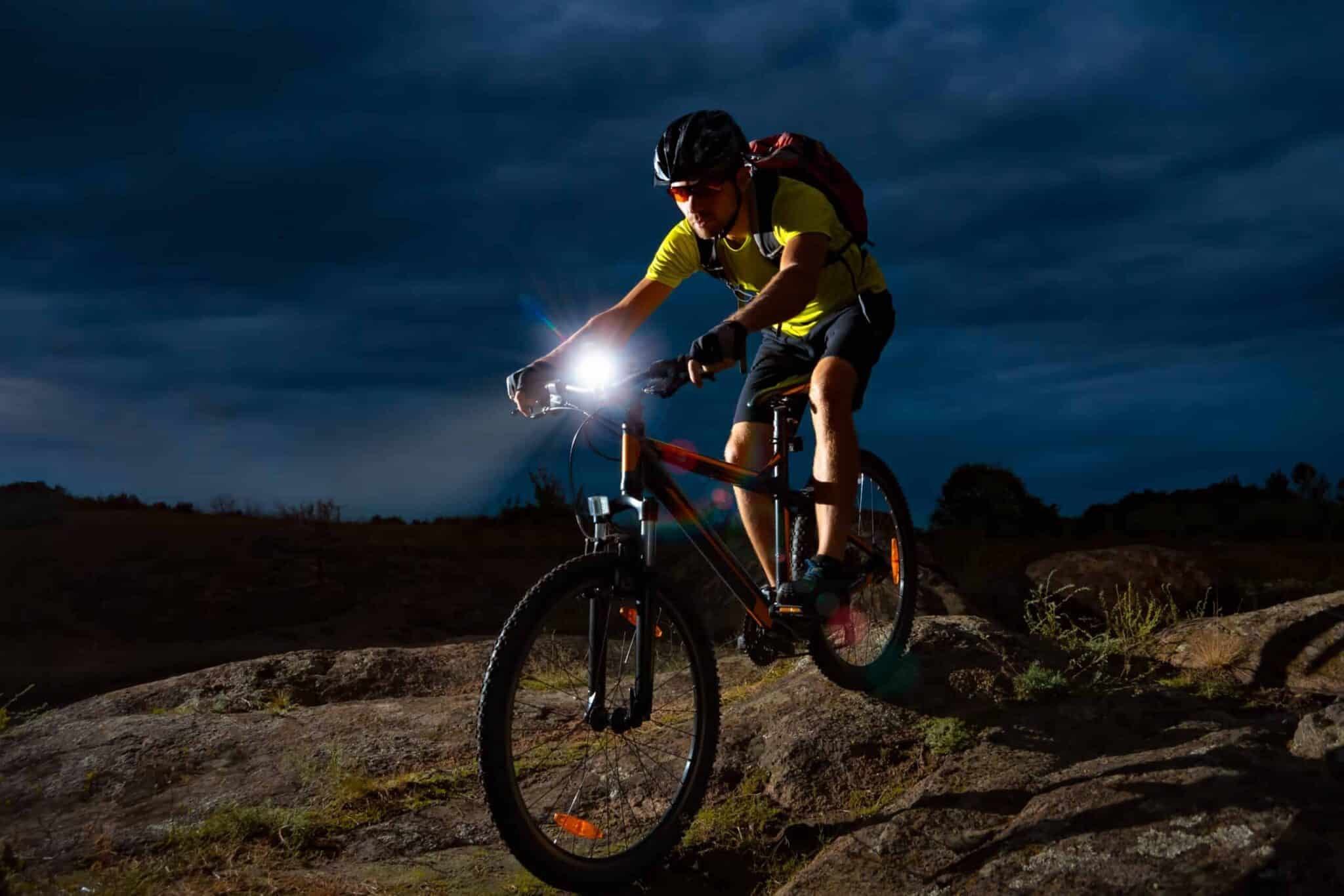 Cyclist Riding the Mountain Bike on Rocky Trail at Night. Extreme Sport and Enduro Biking Concept.
