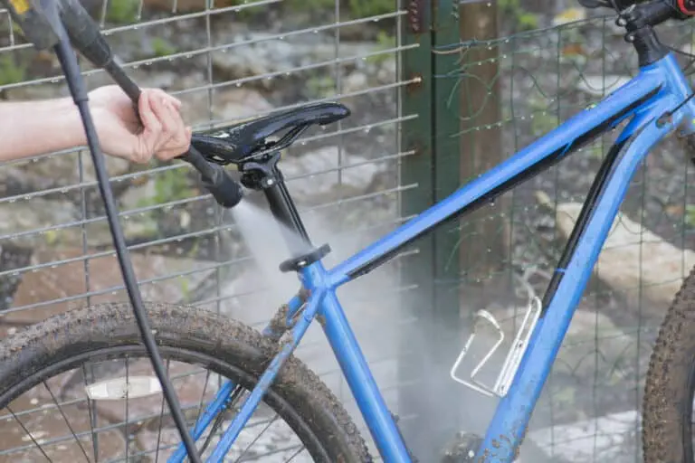 Man cleaning blue bicycle using high pressure washer