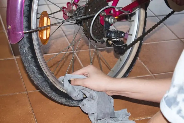 Person holding gray textile near bicycle wheel