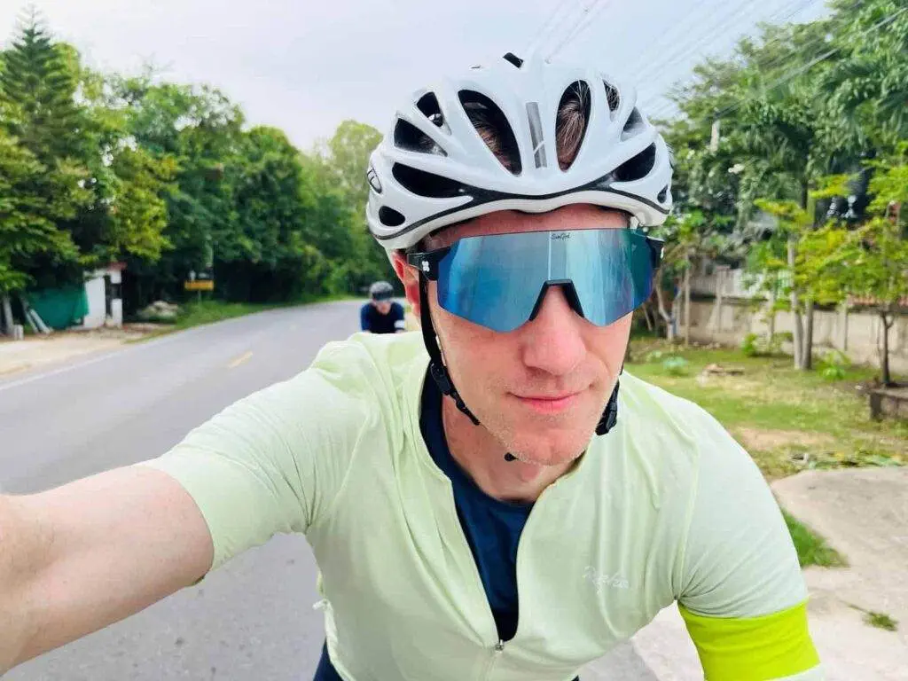A man is taking a selfie while riding his bike. A man is taking a selfie while riding his bike.