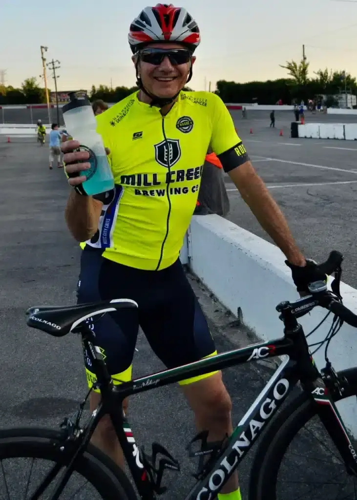 Jay holding a bottle of something posing with a Colnago bike