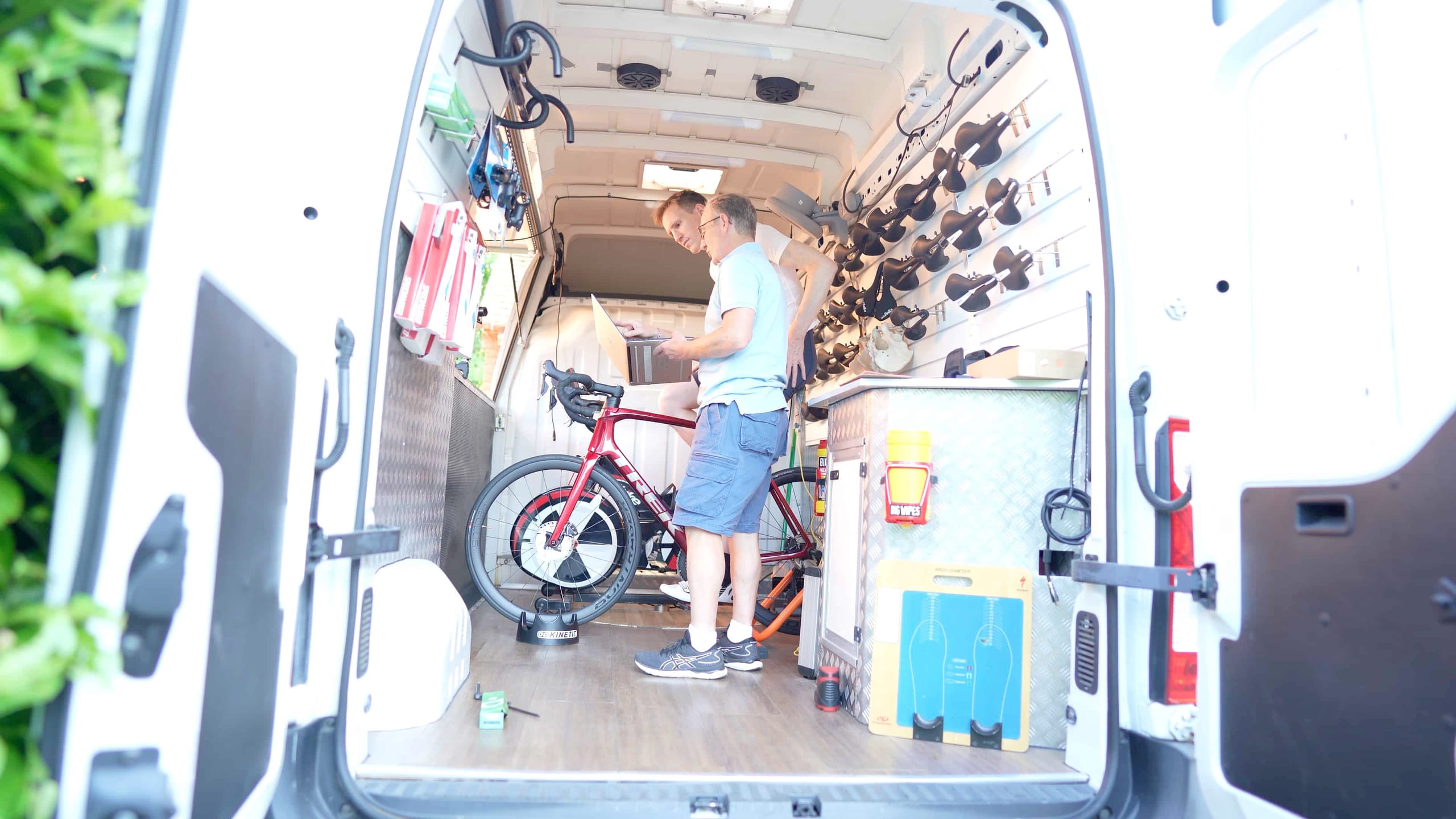 side view of cyclist and bike fitter checking saddle pressure map test results