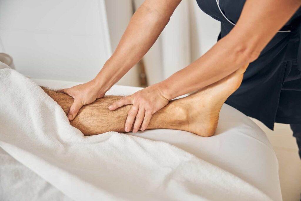 A woman giving a massage to a man’s leg.