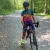 Amanda, an avid cyclist, stands out in vibrant gear and helmet among fellow riders on a forest gravel path with her bike.